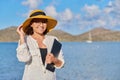 Portrait of happy mature woman in straw hat with laptop on the beach, copy space Royalty Free Stock Photo