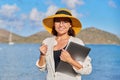 Portrait of happy mature woman in straw hat with laptop on the beach Royalty Free Stock Photo