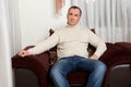 Portrait of happy mid adult man sitting on sofa at home. Handsome Caucasian man in casual relaxing on couch and smiling. Cheerful Royalty Free Stock Photo