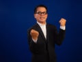 Portrait of happy middle-aged asian confident successful businessman wearing suit celebrating on blue background in studio, Royalty Free Stock Photo