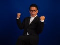 Portrait of happy middle-aged asian confident successful businessman wearing suit celebrating on blue background in studio, Royalty Free Stock Photo