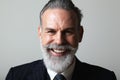 Portrait of happy middle aged bearded gentleman wearing trendy suit over empty gray background. Studio shot, business