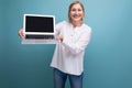 portrait of happy middle aged business woman with blond hair using laptop with mocup