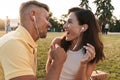 Portrait of happy middle-aged couple man and woman laughing and listening to music together with earphones in summer park Royalty Free Stock Photo