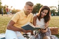 Portrait of happy middle-aged couple man and woman smiling and reading books in summer park Royalty Free Stock Photo