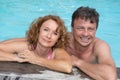 Portrait of happy middle aged couple relaxing on the edge of swimming pool Royalty Free Stock Photo