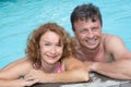 Portrait of happy middle aged couple relaxing on the edge of swimming pool Royalty Free Stock Photo