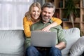 Portrait Of Happy Middle Aged Couple Using Laptop At Home Royalty Free Stock Photo