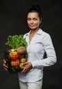 Portrait of a happy middle-aged woman in apron holds a basket of fresh vegetables and fruit Royalty Free Stock Photo