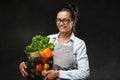 Portrait of a happy middle-aged woman in apron holds a basket of fresh vegetables and fruit Royalty Free Stock Photo