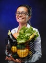 Portrait of a happy middle-aged woman in apron holds a basket of fresh vegetables and fruit Royalty Free Stock Photo