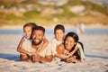 Portrait of a happy mixed race family lying together on the beach. Little girl and boy lying on their parents while Royalty Free Stock Photo