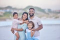 Portrait of a happy mixed race family standing together on the beach. Loving parents spending time with their two Royalty Free Stock Photo