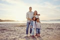 Portrait of a happy mixed race family standing together on the beach. Parents spending time with their cute son and Royalty Free Stock Photo