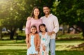 Portrait of a happy mixed race family standing together in a public park on a sunny day. Asian parents and two little Royalty Free Stock Photo