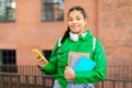 Portrait of happy mixed race student lady with smartphone and workbooks posing outdoors near college Royalty Free Stock Photo