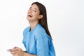 Portrait of happy modern girl with phone, smiling and laughing, looking carefree, wearing blue t-shirt. Celullar company