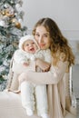 Portrait of a happy mother and a charming child celebrating Christmas. New year holiday. Baby with mom in a festively decorated