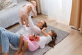 Portrait of happy mother and children playing in the living room resting on the floor, mommy raising arms and holding infant baby Royalty Free Stock Photo