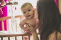 Portrait of a happy mother with cute baby in crib giving kiss Royalty Free Stock Photo