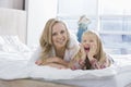 Portrait of happy mother and daughter lying in bed Royalty Free Stock Photo