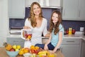 Portrait of happy mother and daughter preparing fruit juice