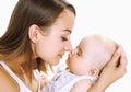 Happy mother holding on hands and kissing her little sleeping baby on a white background Royalty Free Stock Photo