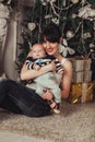 Portrait of happy mother and litle baby near decorated christmas tree with gifts. Royalty Free Stock Photo