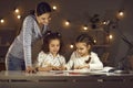 Portrait of happy mother watching two daughters children drawing picture
