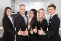 Happy Business People Gesturing Thumbs Up In Office Royalty Free Stock Photo