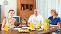 Portrait of happy multigeneration family eating friuts with jui