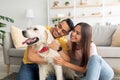 Portrait of happy multiracial couple scratching their pet dog, sitting on floor at home Royalty Free Stock Photo