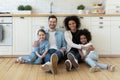 Portrait happy multiracial family sitting on floor in kitchen Royalty Free Stock Photo