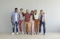 Portrait of happy multiracial friends standing embracing against the backdrop of a light wall.