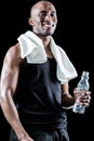 Portrait of happy muscular man with towel around neck holding bottle Royalty Free Stock Photo