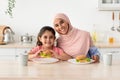 Happy Muslim Mom In Hijab And Little Daughter Eating Sandwiches In Kitchen