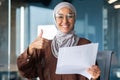 Portrait of a happy Muslim woman in a hijab, a student holding a document, a letter, a sheet of paper in her hands Royalty Free Stock Photo