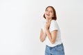 Portrait of happy natural girl, laughing and smiling at camera, holding hands pressed to chest. Beautiful lady express