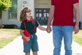 Portrait of happy nerd pupil holding teachers hand. American father and son walking trough school park. Royalty Free Stock Photo