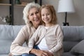 Portrait of happy old grandmother and small granddaughter on sofa Royalty Free Stock Photo