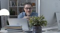 Portrait of happy older man in glasses at desk at home Royalty Free Stock Photo