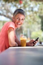 Happy older woman sitting outside with drink and using mobile phone Royalty Free Stock Photo