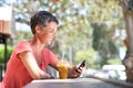 Happy older woman sitting outside with mobile phone and drink Royalty Free Stock Photo