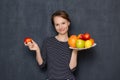 Portrait of happy optimistic girl smiling and holding dish of fruits Royalty Free Stock Photo