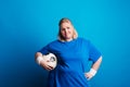 Portrait of a happy overweight woman with a ball in studio on a blue background.