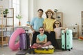 Portrait of happy young mom, dad and children with packed suitcases in the living-room