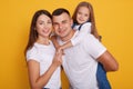 Portrait of happy parents, daddy carries their beautiful daughters on his back. Lovely family of three pose together against Royalty Free Stock Photo