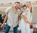 Portrait of happy parents giving their little children piggyback rides outside in a garden. Smiling caucasian couple Royalty Free Stock Photo