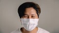 Portrait of a Happy Person, Wearing a Surgical Mask, Standing against the White Wall, Smiling inside a Mask