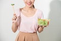 Portrait of a happy playful girl eating fresh salad from a bowl and winking isolated over white background Royalty Free Stock Photo